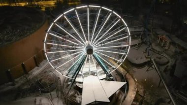 Helsinki. Finlandiya-18 Ocak 2022: Linnanmaki eğlence parkının kışın insansız hava aracı çekimi. Işıklı dönme dolap. Eğlence. Gece vakti. Kamera yavaşça geriye hareket ediyor.