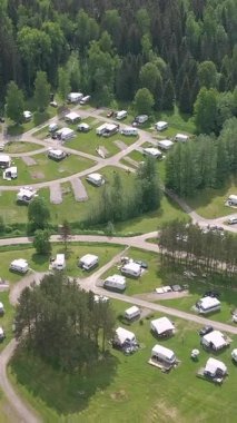 Ormanın ortasında bir karavan parkının güzel insansız hava aracı görüntüsü. Harika bir karavan yaşam tarzı ve iyi bir tatil fırsatı. Kamerayla birlikte hava jeolojisi yavaş yavaş geriye doğru hareket ediyor. Dikey