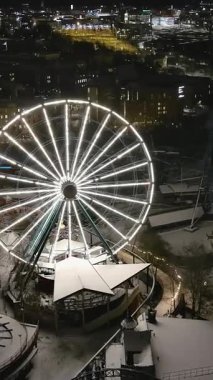 Helsinki. Finlandiya-18 Ocak 2022: Helsinki 'deki karlı Linnanmaki eğlence parkının insansız hava aracı görüntüleri. Gece vakti. Kışın kapalıydı. Eğlence. Dönme dolap. Kamera ileri gidiyor. Dikey video