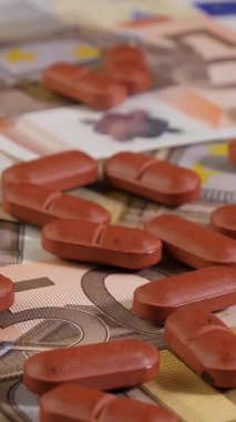 50 avroluk banknotların üzerindeki kahverengi hapları yakından çek. Stüdyo çekimi. İnsanların pahalı ilaç ve sağlık hizmetleri konsepti için yeterli parası yok. Kamera yavaşça yakınlaştırılıyor. Dikey video