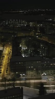 Helsinki. Finlandiya-18.2022: Helsinki şehir merkezinde tramvay sürüşünün yüksek açılı görüntüsü. Tramvay. Gece vakti. Şehir manzarası. İnsansız hava aracı yavaşça yana hareket ediyor. Dikey video