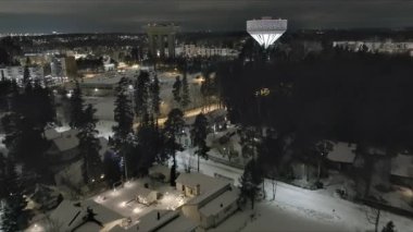 Vanta.Finlandiya-29 Aralık 2021: Hiekkaharju Vantaa 'daki eski su kulesinin yanında yeni su kulesinin yüksek açılı görüntüsü. Güzel şehir manzarası. Gece vakti. Kış zamanı. İnsansız hava aracı yavaşça ilerliyor.