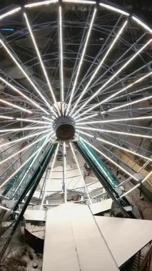 Helsinki. Finlandiya-18 Ocak 2022: Linnanmaki eğlence parkının kışın insansız hava aracı çekimi. Işıklı dönme dolap. Eğlence. Gece vakti. Kamera yavaşça geriye doğru hareket ediyor. Dikey çekim