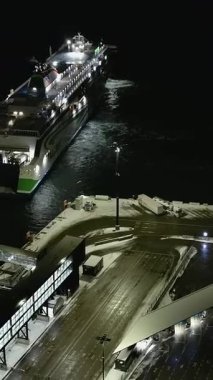 Helsinki. Finlandiya-18 Ocak 2022: Helsinki Finlandiya 'da Lansisatama' ya yanaşan bir geminin insansız hava aracı görüntüsü. Ulaşım. Kış zamanı. Batı limanı. Gece vakti. Kamera yavaşça geriye doğru hareket ediyor. Dikey çekim
