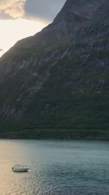 Zaman ayarlı. Kıyıdan uzakta küçük bir balıkçı teknesi. Hızlı su hareketi. Uzaklaş. Dikey video.