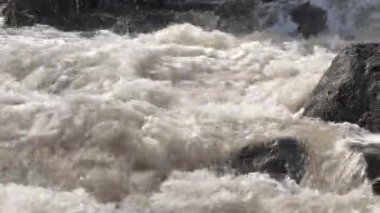 Kayaların arasına su sıçrayan yakın çekim. Jeoloji kamerası yavaşça sağa dönüyor..