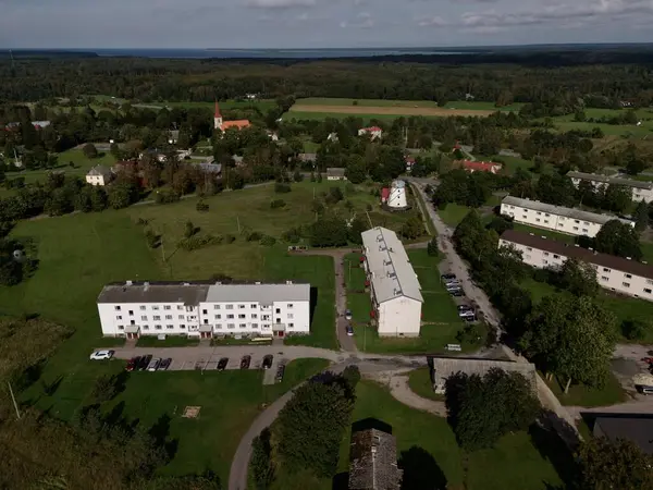 Mustjala, Estonia-September 12, 2025: Aerial view revealing a tranquil residential area with apartment buildings set against lush greenery, agricultural fields, and the serene Baltic Sea in Estonia