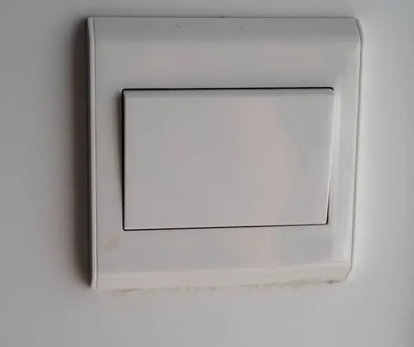 Detail of white light switch on white wall