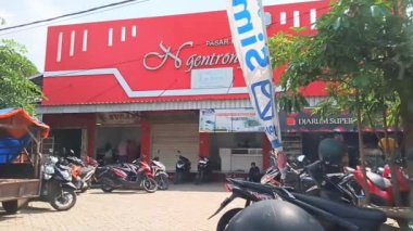 Tulungagung - 10 Ocak 2024: Güneşli köy pazarı, kavurucu güneşin altında geleneksel koşuşturma, gölgeli tüccarlar ve park etmiş motosikletler