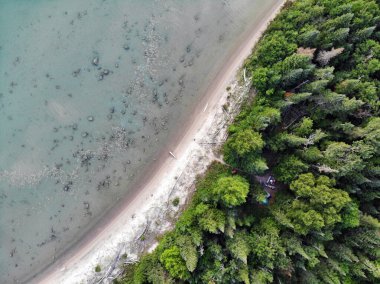 Superior Gölü 'ndeki uzak kumsalın tepeden aşağı manzarası. Çam ormanı ve küçük bir açıklıkta kamp alanı var.