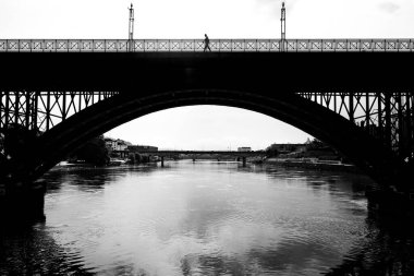 Maribor şehrindeki eski köprüde Drava nehri olan bir adamın silüeti.