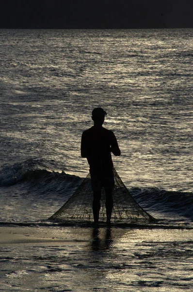 silhouette of fisherman on a beach