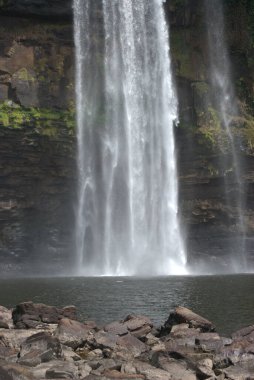 Bir şelale. Önünde bir insan duruyor.