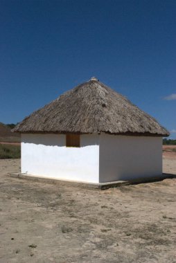 Sazdan çatılı küçük beyaz bir bina.