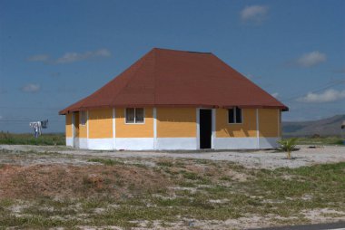 Kırmızı çatılı küçük sarı ve beyaz bir ev.