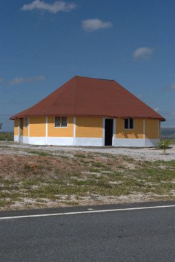 Kırmızı çatılı küçük sarı bir bina.