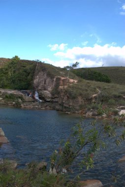 Şelalesi olan bir nehir ve kayanın üzerinde oturan bir insan.