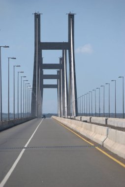 Gökyüzü arkaplanı olan bir köprüde giden bir araba.