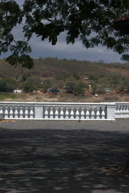 Ağacın altındaki bankta oturan bir adam.