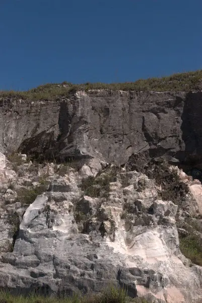 Sörf tahtasıyla kayanın üzerinde duran bir adam.