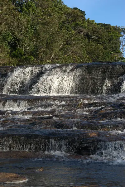 Nehrin ortasındaki bir kayanın üzerinde duran bir adam.