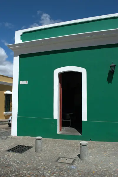 a green building with a white trim and a red door