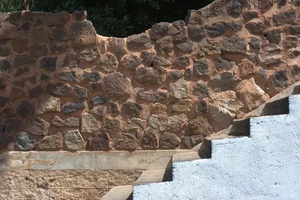 Taştan bir duvar ve ona doğru giden adımlar.