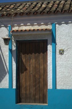 Beyaz mavi ve sarı duvarlı tahta bir kapının dikey görüntüsü.