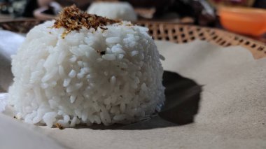 Bir kasede küflenmiş pirinç, yağlı kağıt kaplı bir rattan tabakta servis edilir.