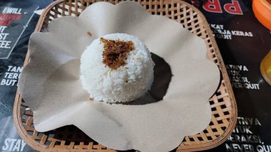 Bir kasede küflenmiş pirinç, yağlı kağıt kaplı bir rattan tabakta servis edilir.