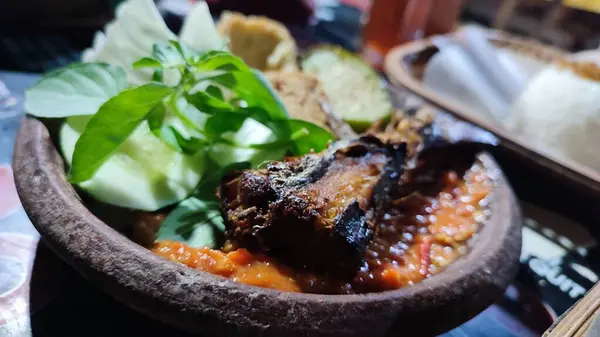 Lalapan adlı geleneksel Endonezya yemeği ahşap tabakta ızgara tavuk ve ızgara balık, sebze, kızarmış tempeh ve baharatlı acı biber soslu pilav var.