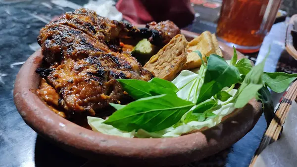 Lalapan adlı geleneksel Endonezya yemeği ahşap tabakta ızgara tavuk ve ızgara balık, sebze, kızarmış tempeh ve baharatlı acı biber soslu pilav var.