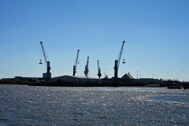 Hamburg. Vinçler Elbe Nehri 'nde, limanda. Mavi gökyüzü ve su. Suyun güzel bir fotoğrafı..
