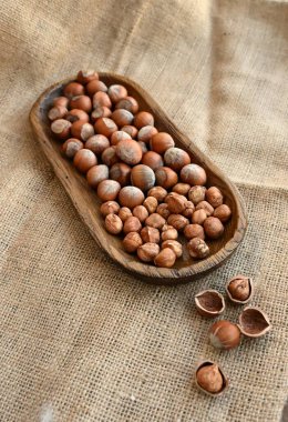 Çuval bezinde tahta tepside fındık. Sağlıklı ev yapımı tarifler ve yavaş yaşam veren mutfak estetiği için doğal gıda malzemeleri..