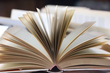 Kitap yığını, kapatın. Kütüphanede masanın üzerinde açık bir kitap. Okul konseptine geri dönelim. Masada bulanık kitaplık arkaplanı olan bir kitap aç. Kütüphanede beyaz masa üzerine açık kitap