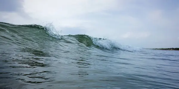 a wave breaking in the ocean with a person on a surfboard