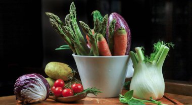 Siyah taş masadaki cam kasede taze organik sebzeler.