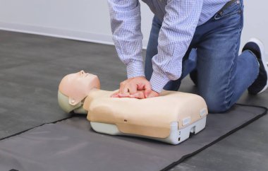 Erkek fizyoterapist ilk yardım eğitiminde mankenlere kalp masajı yapıyor.