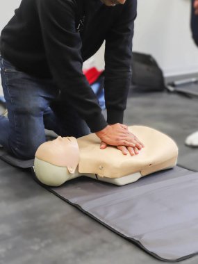 Erkek fizyoterapist ilk yardım eğitiminde mankenlere kalp masajı yapıyor.