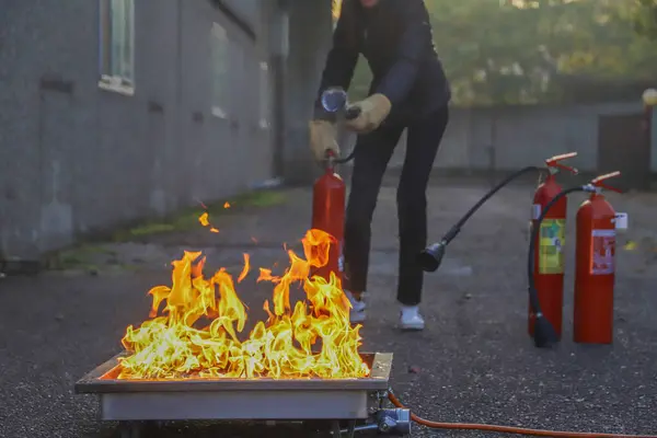 Yanan ateşle yangın söndürücü. şirket güvenliği - itfaiye kursu sırasında egzersiz