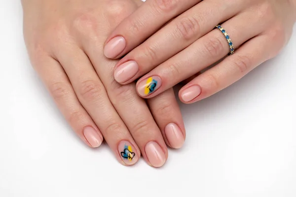 Natural beige manicure on short oval nails. Ukrainian symbols. Yellow blue drawing. Heart drawing.