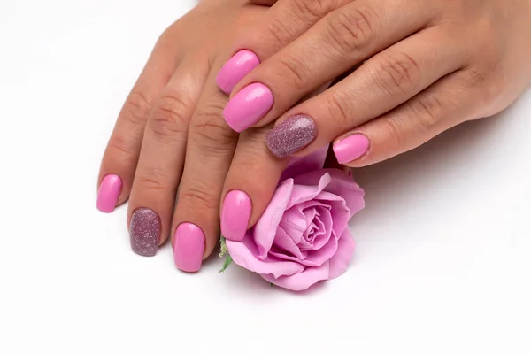 Gently pink manicure with shimmer with a rose in the palm of your hand on long square nails close-up on a white background