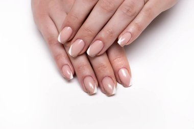Beyaz bej parlak Fransız manikürü, beyaz arka planda kısa kare tırnaklar.