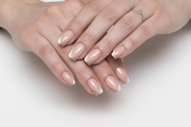 Beyaz bej parlak Fransız manikürü, beyaz arka planda kısa kare tırnaklar.