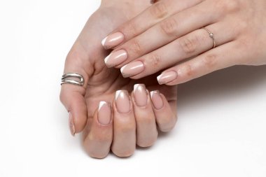 Beyaz bej parlak Fransız manikürü, beyaz arka planda kısa kare tırnaklar.