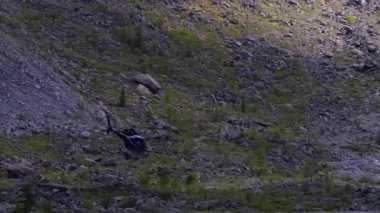 Helikopter yüksek dağların arasında uçar.