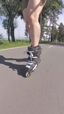 Kadın bacaklarına yakın çekim. Yaz aylarında paten kayan kadınlar. Dikey video