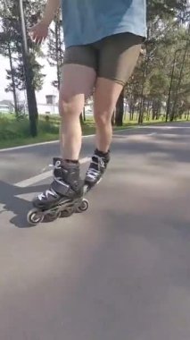 Kadın bacaklarına yakın çekim. Yaz aylarında paten kayan kadınlar. Dikey video