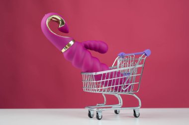Pembe arka planda minyatür alışveriş arabasında seks oyuncağı