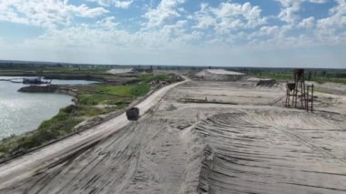 Göl kenarındaki kum ocağına giden bir kamyonun drone görüntüsü.